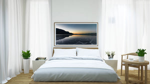 Panoramic Death Valley photograph of blue salt flats and a narrow orange glow on the horizon.