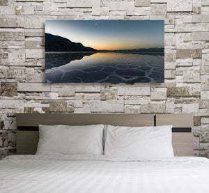 Pale mineral lines form irregular shapes beside a quiet sunset reflection on Death Valley salt flats.