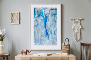 Vertical Antarctic ice photograph showing ridged surfaces and a deep blue glacier opening.