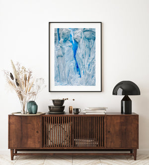 Fine grooves and layered white ice create an abstract pattern around a blue fissure.