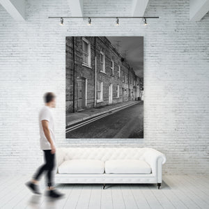 Dusk photograph of Derry terraced houses with receding pavement and road markings.