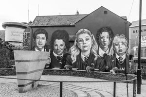 Five painted Derry Girls characters on a building wall in Northern Ireland.