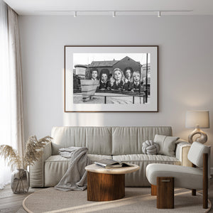 Five expressive painted faces overlooking a Derry street, black and white photograph.