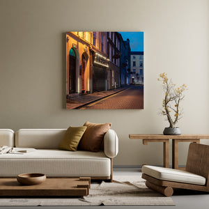 Derry street at dusk with warm foreground light and a pale building in the distance.
