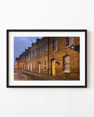Derry terraced houses in warm evening light beneath a cool blue sky.