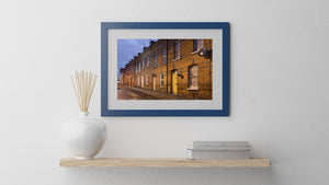 Colour photograph of Derry houses with a yellow doorway and blue evening sky.
