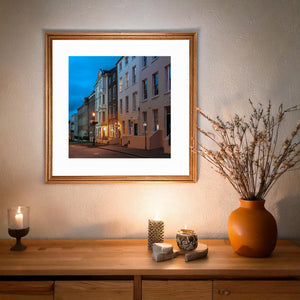 Amber doorway light and pale townhouse walls under blue twilight in Northern Ireland.