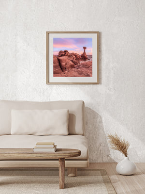 Desert hoodoos at sunset with rounded foreground rock and a solitary capstone column.