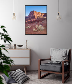 Vertical desert landscape with fine foreground branches and warm red cliffs.