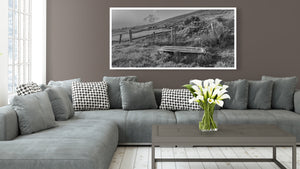 Sloping Irish fields with stone boundaries and weathered fencing in monochrome.