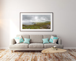 Colour landscape of the Dingle Peninsula with rocks, short grass and a pale bay.