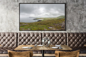 Green Irish fields and a rocky shoreline beneath a broad cloudy sky.