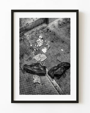 Discarded black shoes on Manhattan pavement in black and white