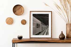 Long train and converging platform beneath a dark station roof