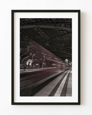 Motion-blurred train beneath Dresden station’s dark roof