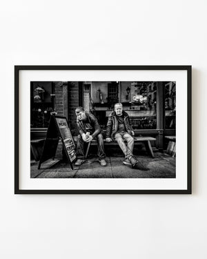Two people seated outside a Dublin cafe in black and white