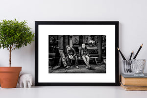Two seated people beneath cafe signs in a Dublin street portrait