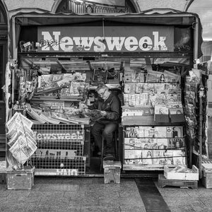 Person reading beside newspaper and magazine racks in Dublin