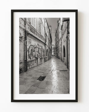 Dubrovnik old town alley with stone paving and graffiti in black and white