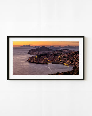Dubrovnik old town beside the Adriatic Sea beneath an orange sunset sky
