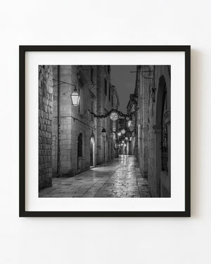 Dubrovnik old town lane at dusk with lanterns and stone paving in black and white