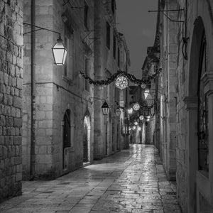 Quiet Dubrovnik alley with hanging lights and weathered stone buildings