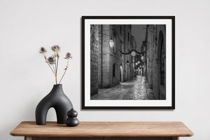 Narrow Dubrovnik old town street at dusk with hanging lights and dark doorways