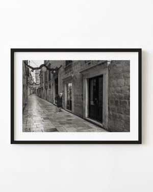 Woman walking along a Dubrovnik stone lane in black and white