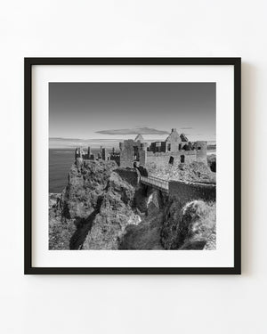 Dunluce Castle ruins and cliffside bridge in black and white