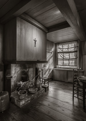Historic Dutch kitchen with a fireplace and sunlit window in sepia