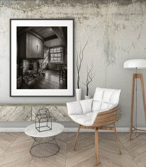 Sepia farmhouse kitchen with a fireplace and worn wooden floor