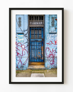 Weathered blue East London door surrounded by red graffiti