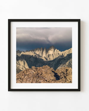 Sunlit Eastern Sierra granite peaks beneath dark storm clouds