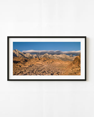 Eastern Sierra peaks beneath a long cloud bank and blue sky