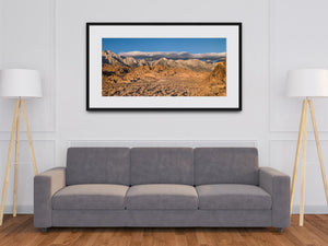 Pale mountain ridges framed by desert rocks and soft clouds