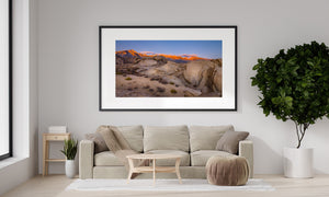 Sunlit Sierra Nevada peaks rising behind a rocky desert landscape