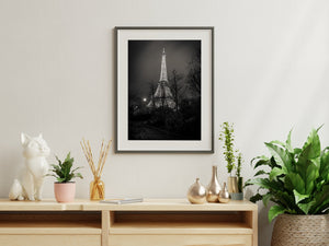 Bright Eiffel Tower ironwork beyond silhouetted winter trees at night