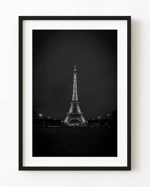 Illuminated Eiffel Tower and starburst street lamps against a dark Paris sky in black and white
