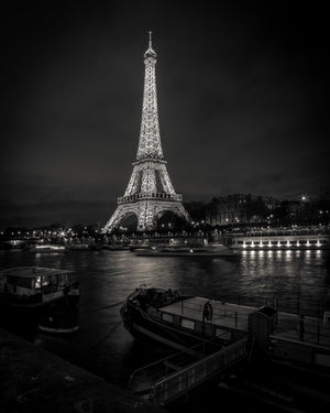 Paris night photograph of the Eiffel Tower across the Seine with boats in the foreground