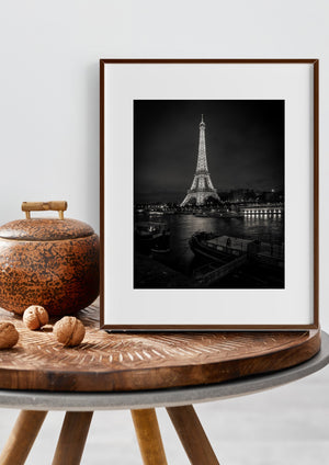 Eiffel Tower shining above the river and moored boats on a dark Paris night