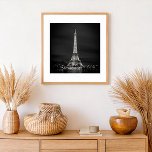 Eiffel Tower glowing beneath a softly clouded sky above dark river reflections