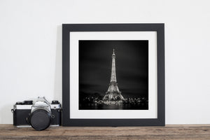 Nighttime Eiffel Tower and small starburst lights along the opposite Seine bank