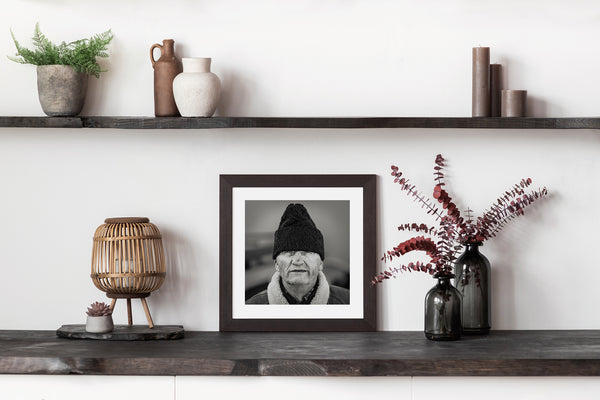 Black and white portrait of elderly man with heavy coat and hat