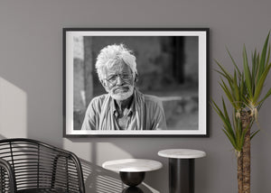 Monochrome photograph of a white-haired Indian man against soft background shadows