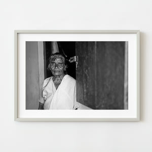 Black and white portrait of elderly woman standing in doorway