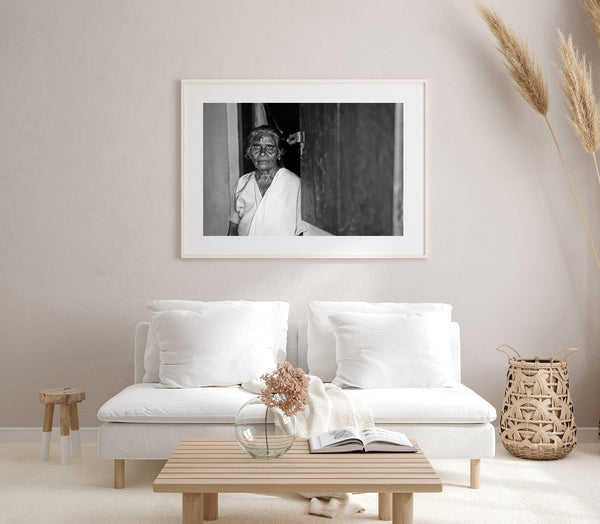 Black and white image of elderly woman by open door in India