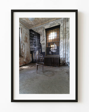 Empty wooden chair in a peeling room at Ellis Island’s abandoned hospital.