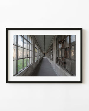 Rows of tall windows recede down an empty corridor at Ellis Island Hospital.