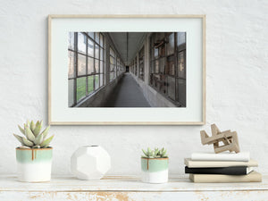 Daylight enters the empty Ellis Island hallway through tall windows on both sides.