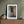 Faint portraits beyond a glass panel contrast with the worn wood of an Ellis Island hospital door.